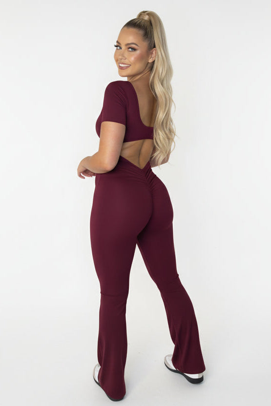 Woman wearing a maroon jumpsuit on a white background