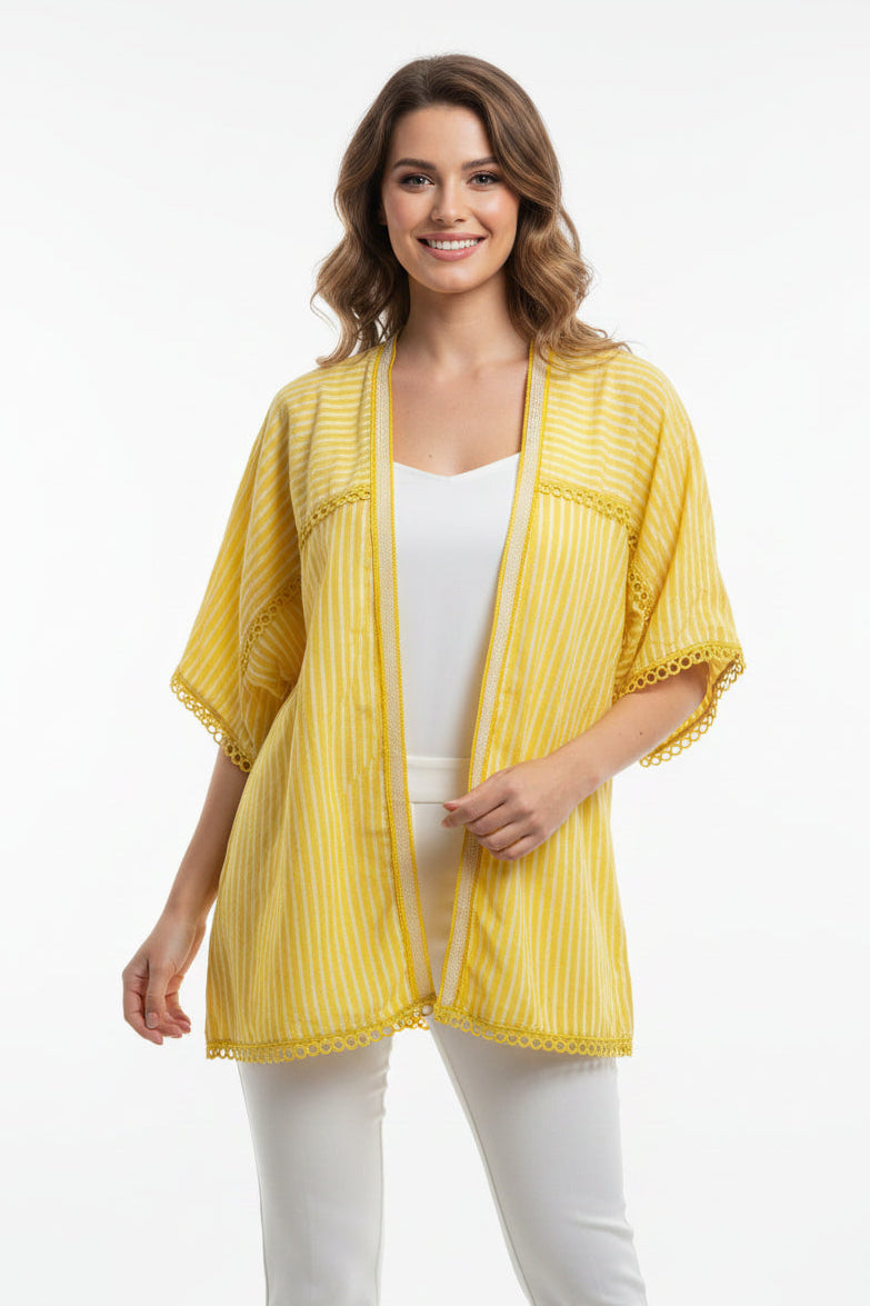 A yellow and white striped short-sleeve blouse with lace trim, hanging on a wooden hanger in a cluttered warehouse or storage room filled with cardboard boxes.
