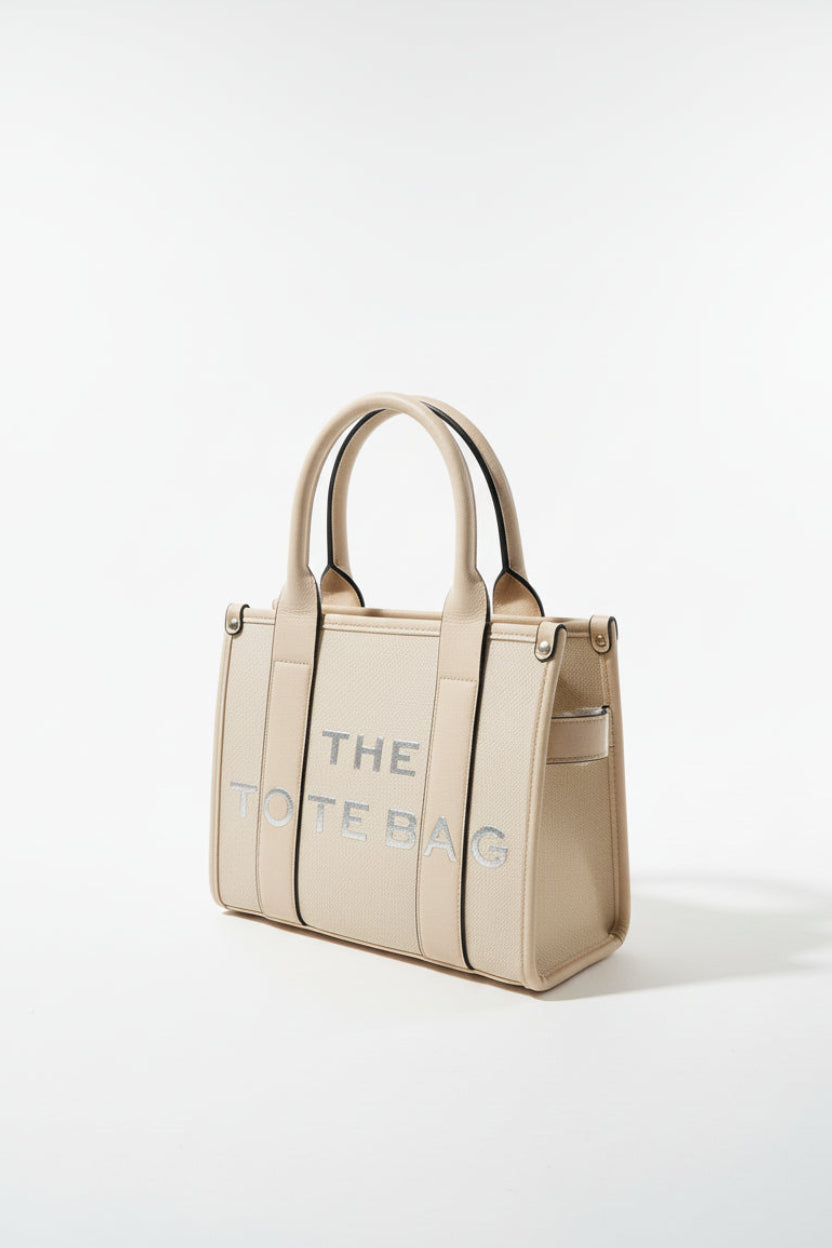 Beige handbag with 'THE BAG' text on a white background