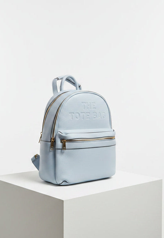 Light blue handbag on a cluttered surface with boxes and papers in the background