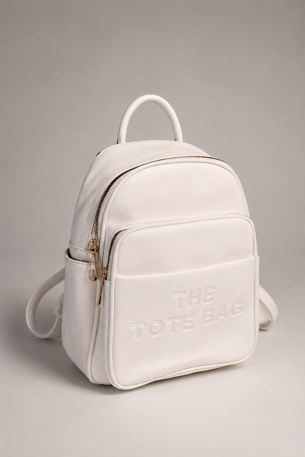 An off-white leather mini backpack with gold-tone hardware and embossed branding on the front pocket, shown against a neutral gray studio background.