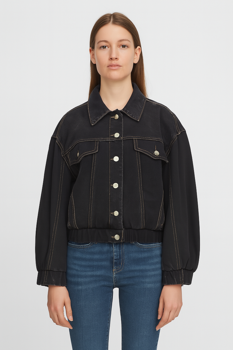 Person wearing a black denim jacket and blue jeans on a light gray background