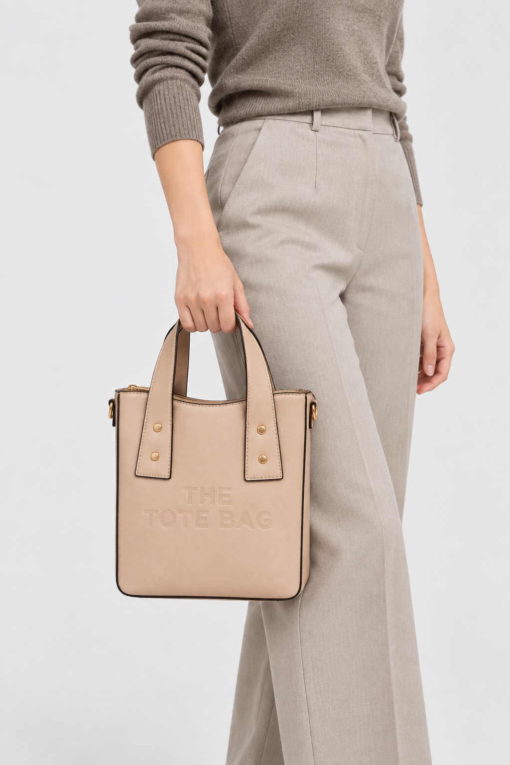 Woman carrying the apricot beige structured tote bag by hand