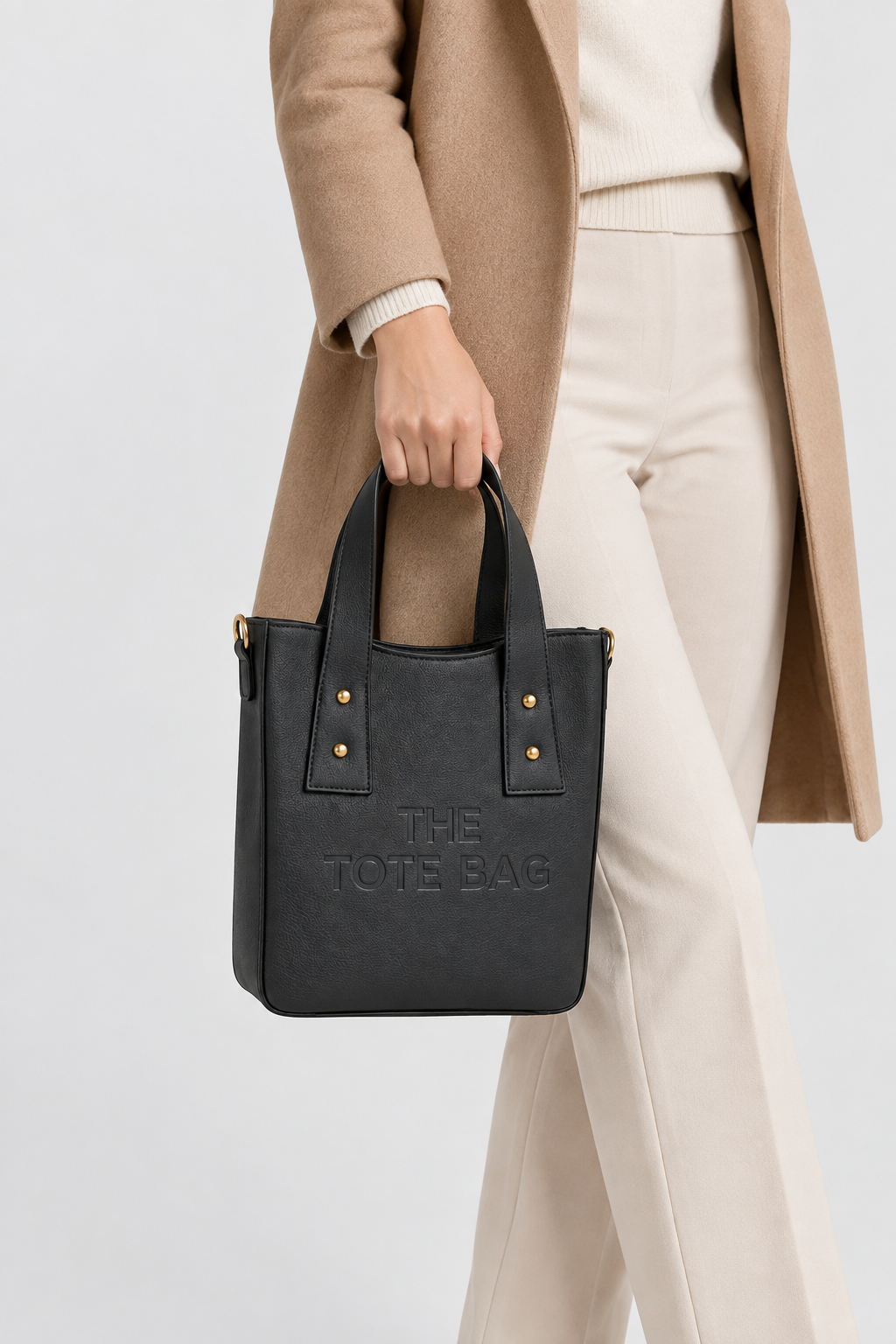 Woman carrying the black structured tote bag by its top handles