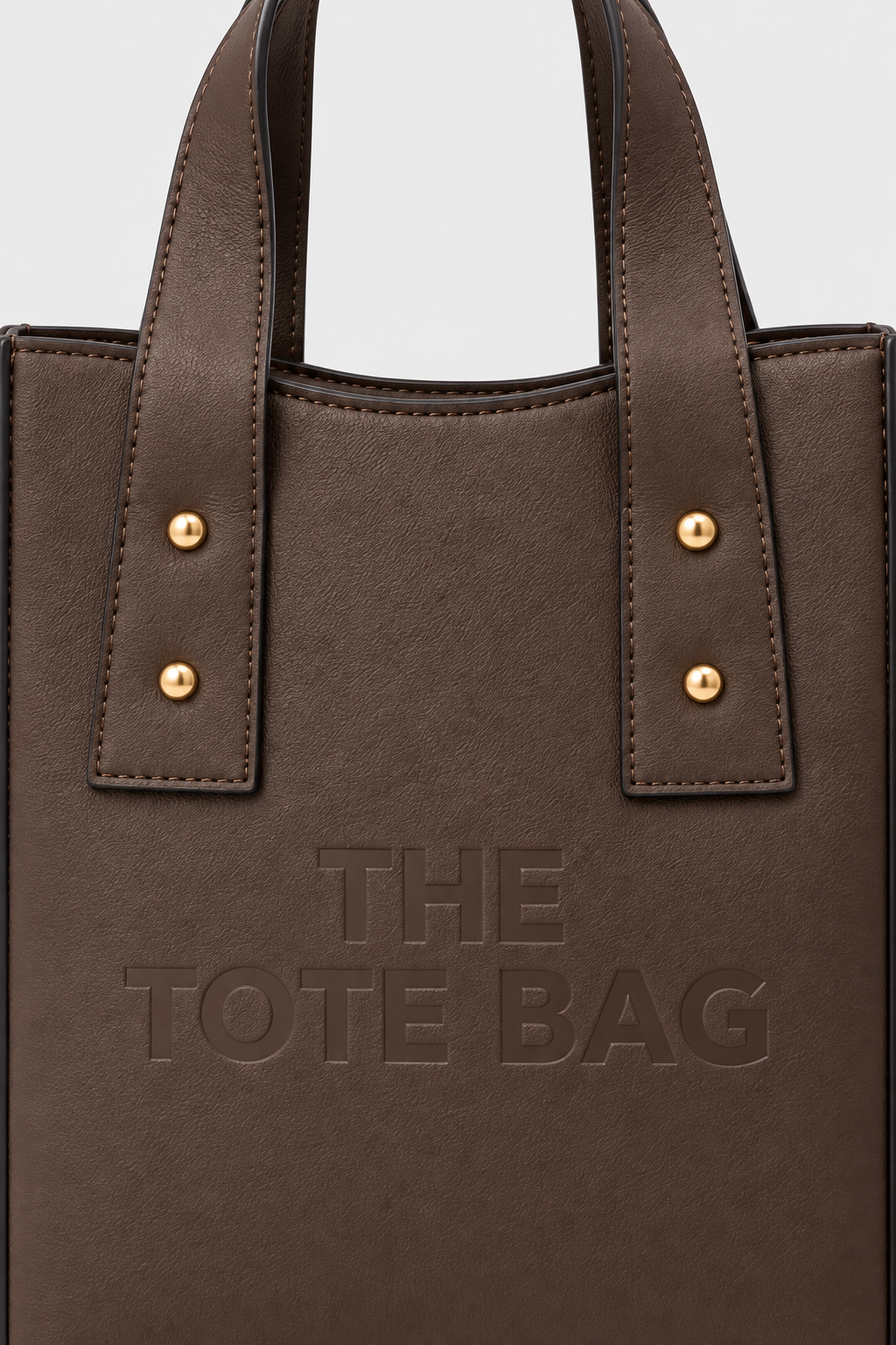 Close-up of coffee brown tote bag texture, stitching and gold-tone studs