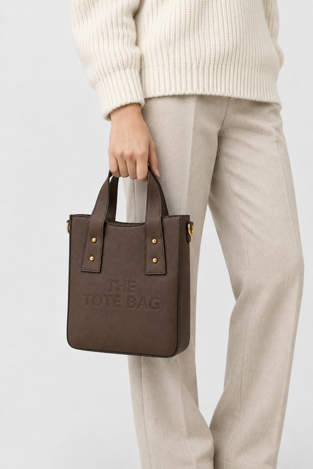 Woman carrying the coffee brown structured tote bag by hand