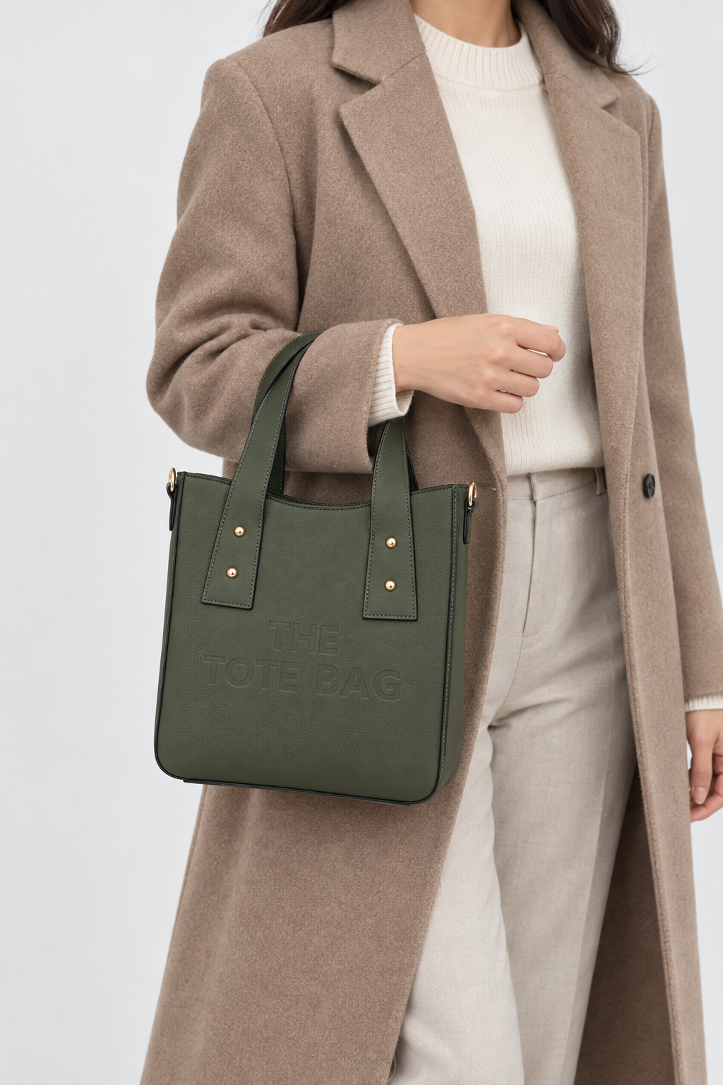 Woman carrying the forest green structured PU tote bag by hand